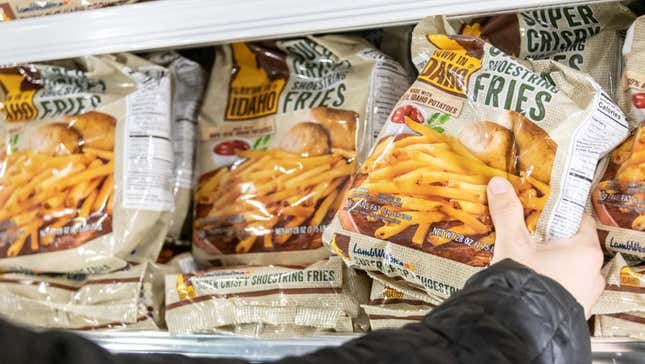 Hand reaching for frozen french fries at grocery store