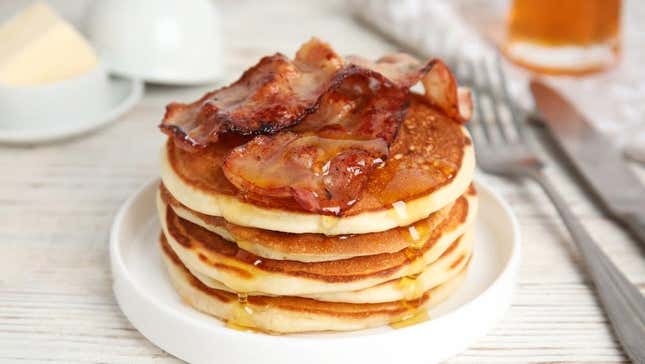 Stack of pancakes at breakfast restaurant topped with bacon